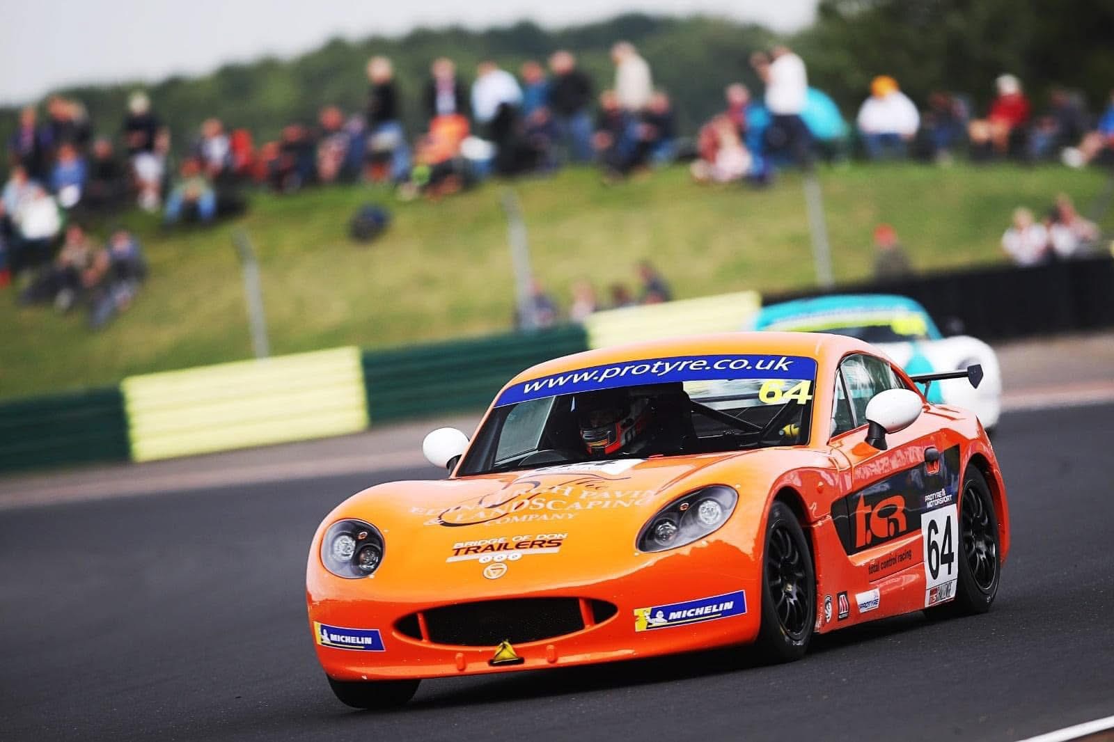 Steven racing the orange number 64 Ginetta